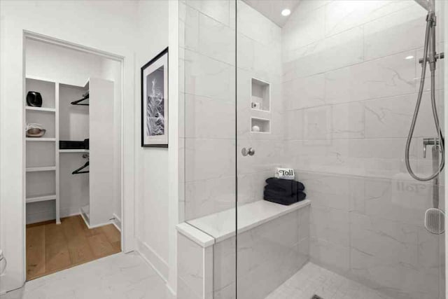 bathroom featuring a tile shower and a walk in closet