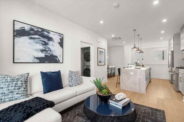 living area featuring recessed lighting, stacked washer and clothes dryer, and light wood-style floors