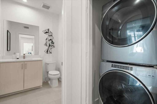 laundry area with sink, stacked washer / drying machine, and light tile patterned flooring