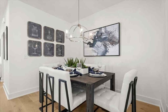 dining space with a chandelier, light wood-style flooring, and baseboards
