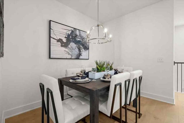 dining area featuring a chandelier, baseboards, and light wood-type flooring