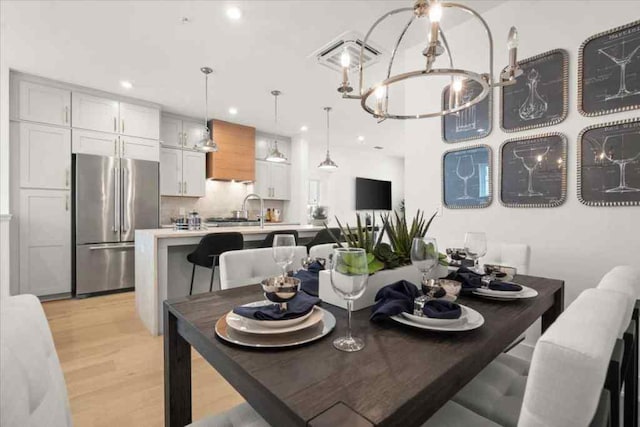 dining space with an inviting chandelier, sink, and light wood-type flooring