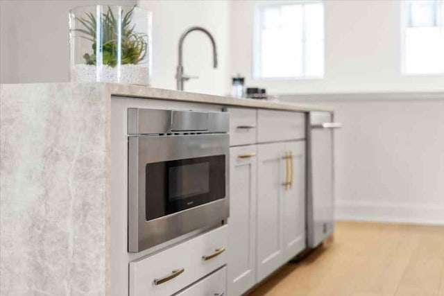 interior details featuring white cabinets, baseboards, stainless steel oven, and light countertops