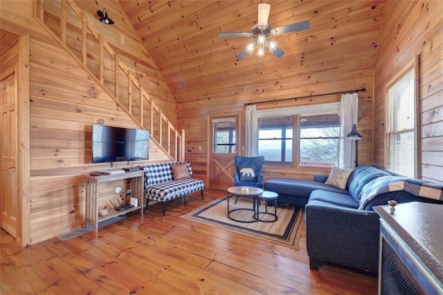 living room with wood walls, wood-type flooring, and high vaulted ceiling