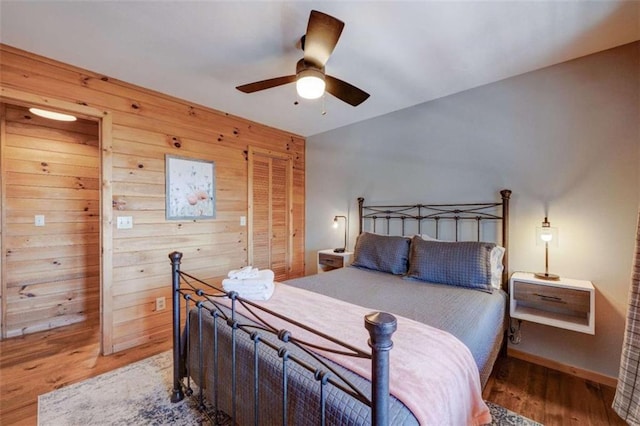 bedroom featuring wood walls, wood finished floors, and a ceiling fan