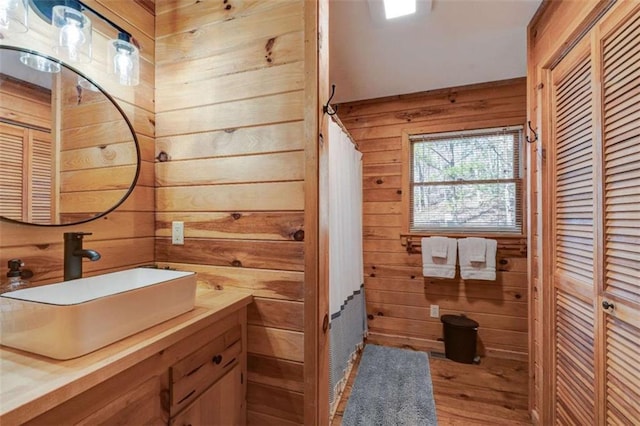 bathroom featuring a closet, wood walls, vanity, and wood finished floors