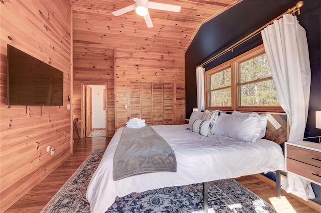 bedroom with high vaulted ceiling, wooden walls, wood finished floors, a ceiling fan, and wood ceiling