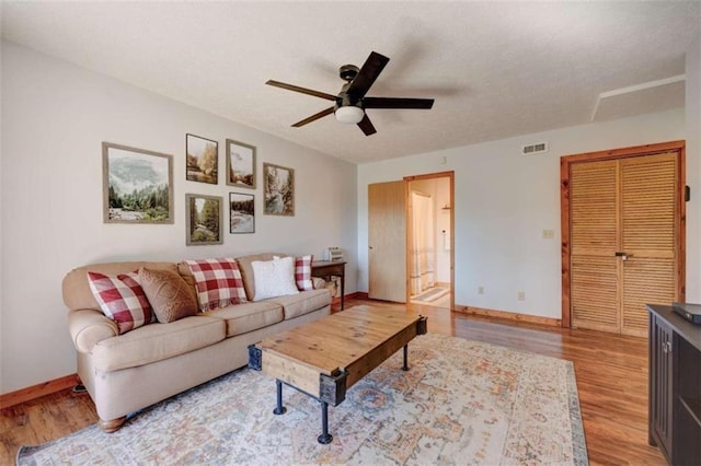 living area featuring light wood-type flooring, ceiling fan, and baseboards