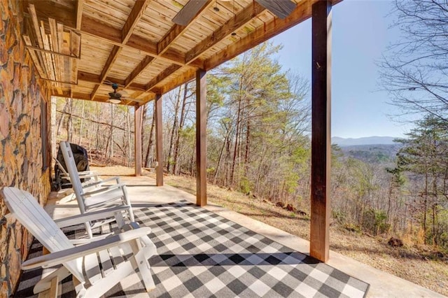 view of patio / terrace with ceiling fan and a view of trees