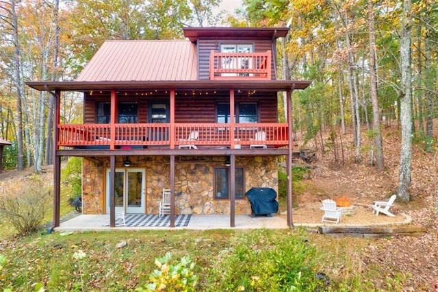 back of house with a patio area, stone siding, metal roof, and log veneer siding