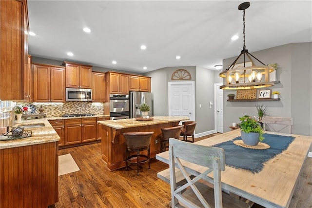 4840 Spring Park Cir, Suwanee, GA 30024 - kitchen with appliances with stainless steel finishes, brown cabinetry, a center island, dark wood-style floors, and backsplash