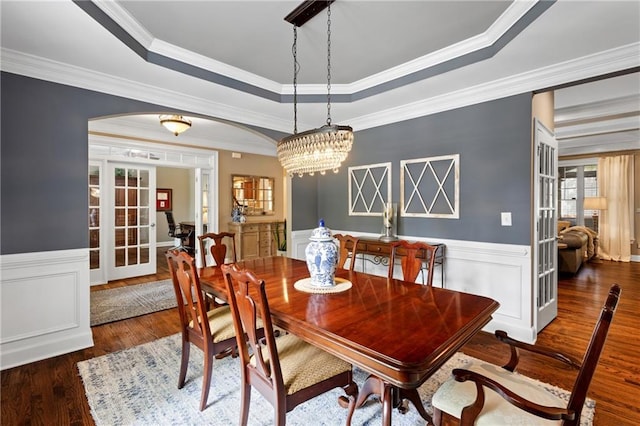 4840 Spring Park Cir, Suwanee, GA 30024 - dining area featuring french doors, wood finished floors, a raised ceiling, arched walkways, and a wainscoted wall