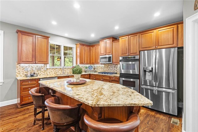 4840 Spring Park Cir, Suwanee, GA 30024 - kitchen with stainless steel appliances, tasteful backsplash, light stone countertops, a kitchen island, and recessed lighting