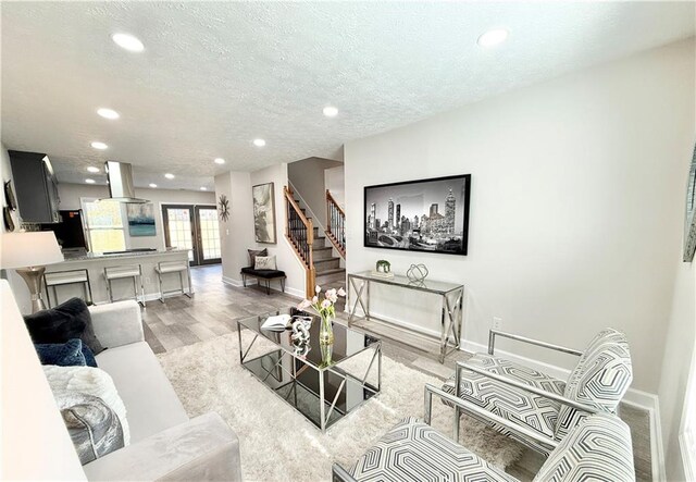 living room featuring a textured ceiling, stairway, recessed lighting, and baseboards