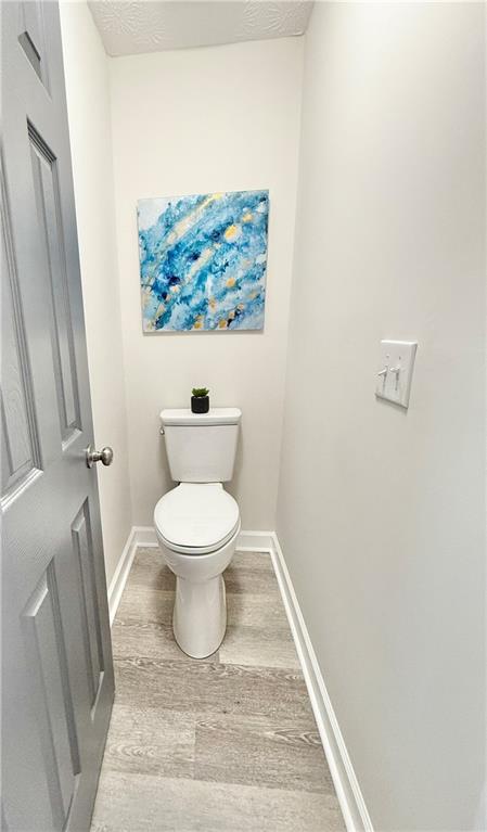 bathroom with baseboards, toilet, and wood finished floors