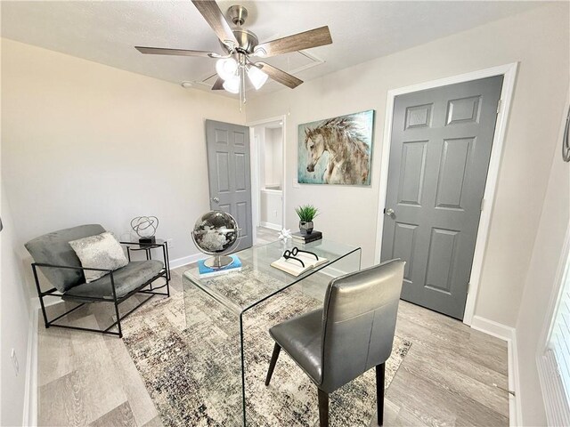 office space featuring baseboards, a ceiling fan, and light wood-style floors