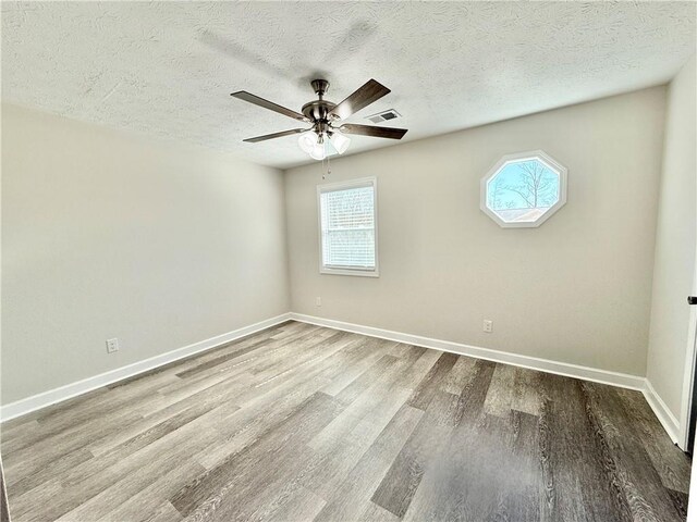 empty room featuring baseboards, visible vents, ceiling fan, and wood finished floors