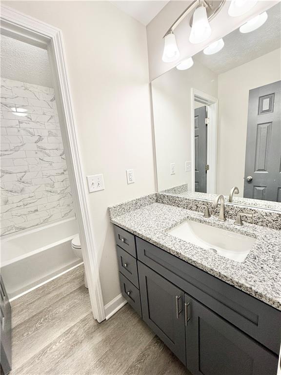 bathroom featuring toilet, a textured ceiling, wood finished floors, and vanity
