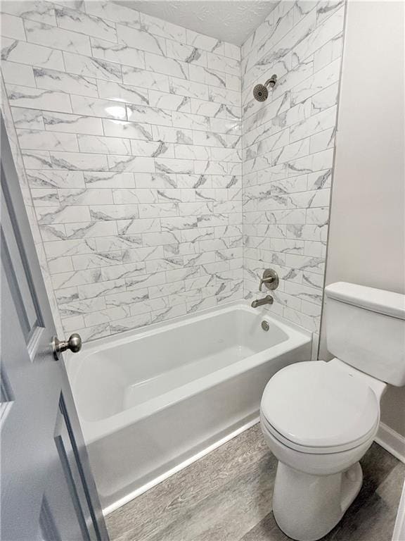 full bath featuring toilet,  shower combination, a textured ceiling, and wood finished floors