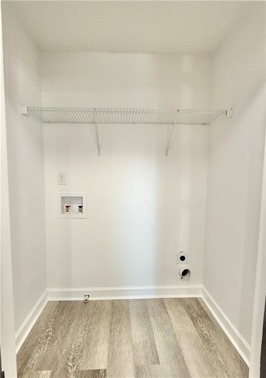 laundry area featuring hookup for an electric dryer, laundry area, washer hookup, wood finished floors, and baseboards