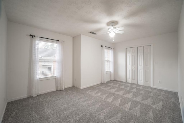 unfurnished bedroom with ceiling fan, carpet flooring, a closet, and a textured ceiling