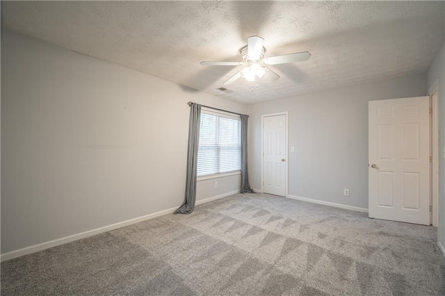 carpeted empty room featuring ceiling fan and a textured ceiling