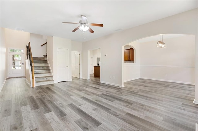 2957 Smith Ridge Trce, Peachtree Corners, GA 30071 - unfurnished living room featuring a ceiling fan, arched walkways, stairs, light wood-style floors, and baseboards