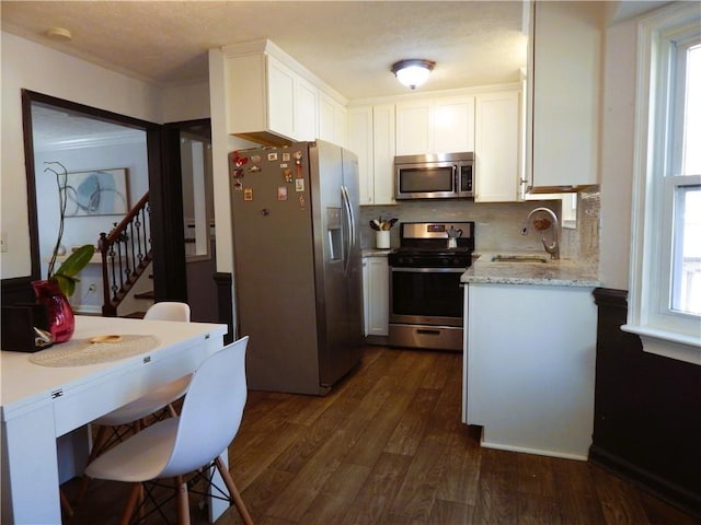 kitchen with a sink, white cabinetry, dark wood finished floors, backsplash, and appliances with stainless steel finishes