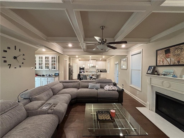 living area featuring coffered ceiling, a high end fireplace, dark wood-style floors, beamed ceiling, and crown molding