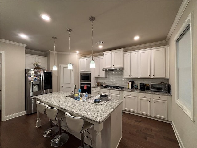 kitchen featuring pendant lighting, white cabinetry, a kitchen bar, stainless steel appliances, and a center island with sink