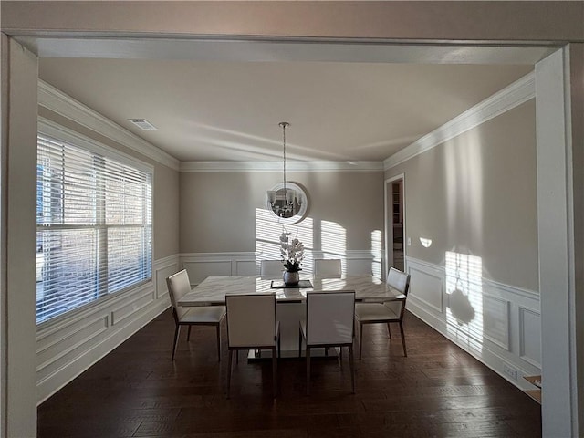 dining area with a wainscoted wall, visible vents, dark wood-style flooring, and crown molding