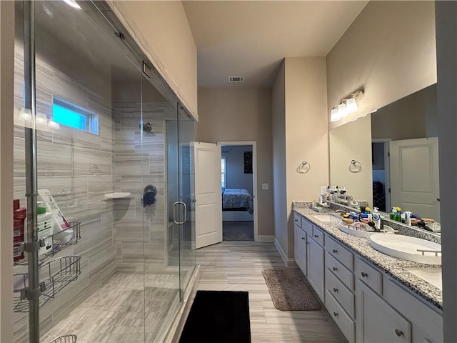 ensuite bathroom with ensuite bathroom, visible vents, baseboards, double vanity, and a stall shower