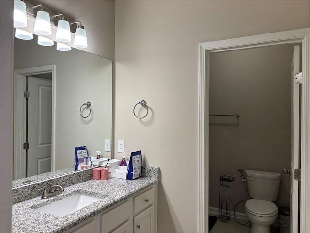 bathroom featuring toilet, baseboards, and vanity