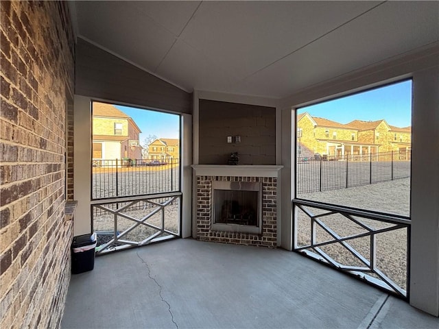 interior space featuring lofted ceiling, a brick fireplace, a residential view, and brick wall