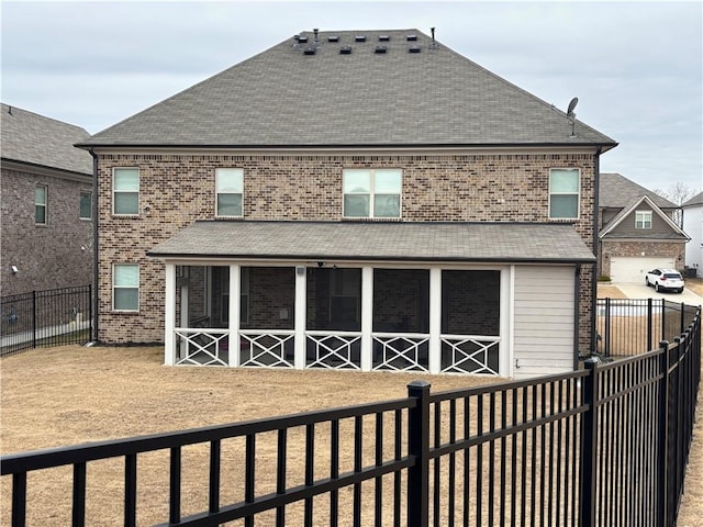 back of house featuring a sunroom, a fenced backyard, and brick siding