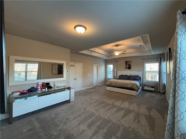 bedroom with a tray ceiling, dark carpet, baseboards, and two closets