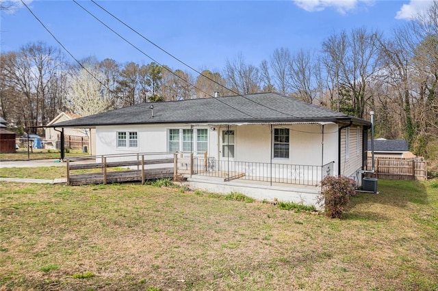 view of front of property with a porch, a shingled roof, a front yard, and fence