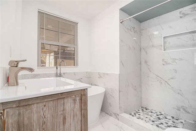 full bathroom featuring vanity, a freestanding bath, a shower, wainscoting, and marble finish floor