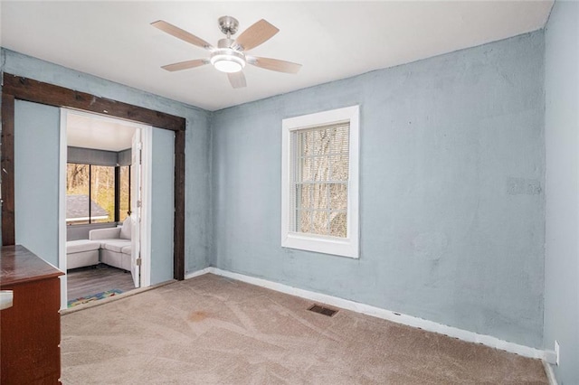 carpeted empty room featuring visible vents, baseboards, and ceiling fan