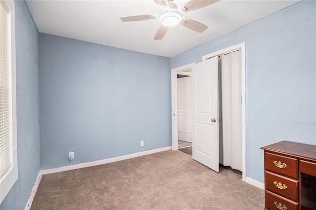 unfurnished bedroom with baseboards, light carpet, and a ceiling fan