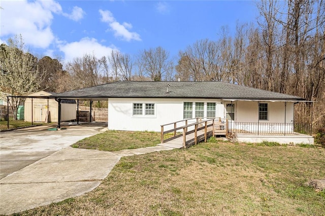 ranch-style home with a porch, concrete driveway, a front yard, a storage shed, and a carport