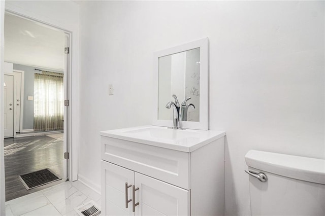 half bath featuring visible vents, baseboards, toilet, marble finish floor, and vanity