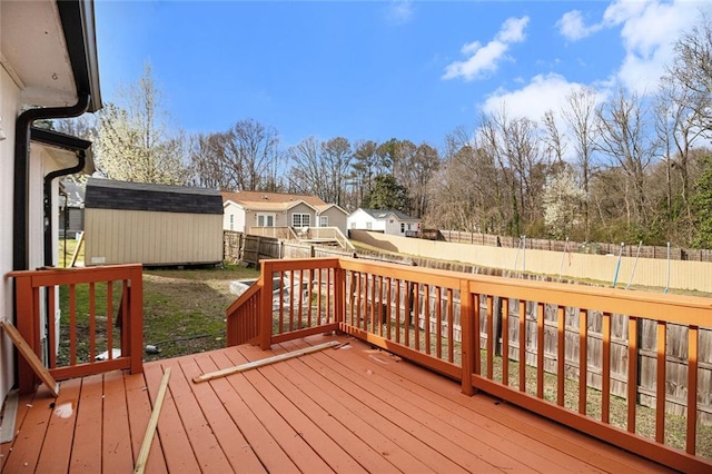 wooden deck featuring a residential view, an outdoor structure, a fenced backyard, and a shed