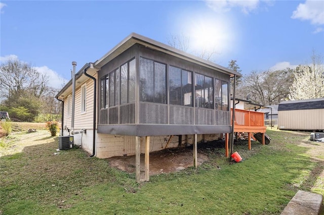 back of property featuring central air condition unit, a sunroom, a storage shed, an outdoor structure, and a yard