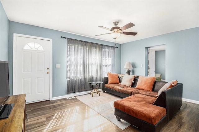 living room featuring baseboards, ceiling fan, and wood finished floors