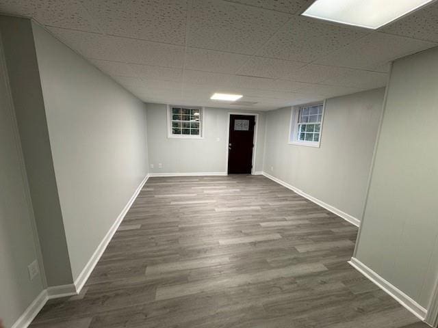 basement featuring a drop ceiling and dark wood-type flooring