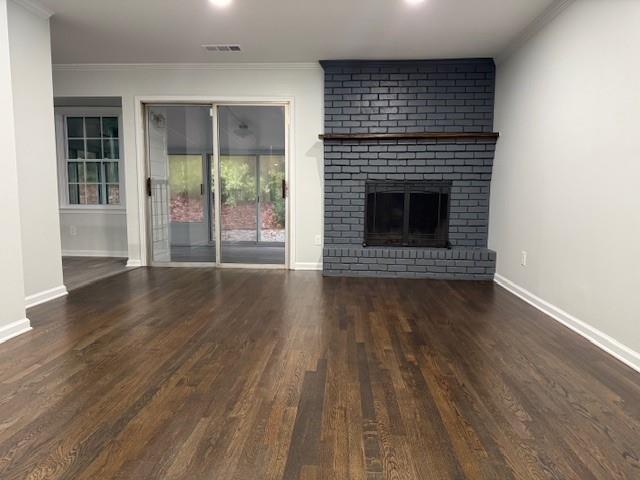 unfurnished living room featuring dark hardwood / wood-style floors, crown molding, and a fireplace