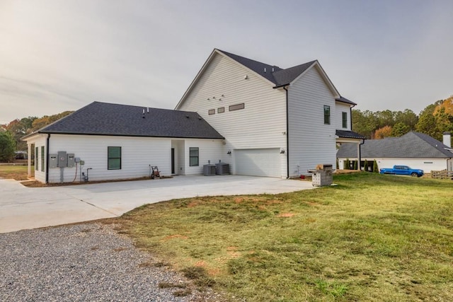 back of property with central air condition unit, a yard, and a garage