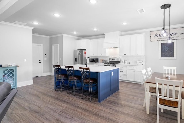 kitchen featuring dark wood-type flooring, stainless steel appliances, a center island with sink, white cabinets, and custom range hood