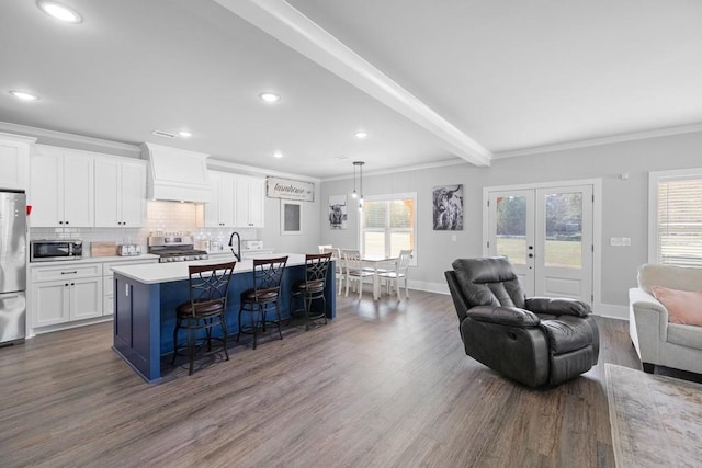 kitchen featuring white cabinetry, stainless steel appliances, dark hardwood / wood-style flooring, a breakfast bar area, and a kitchen island with sink